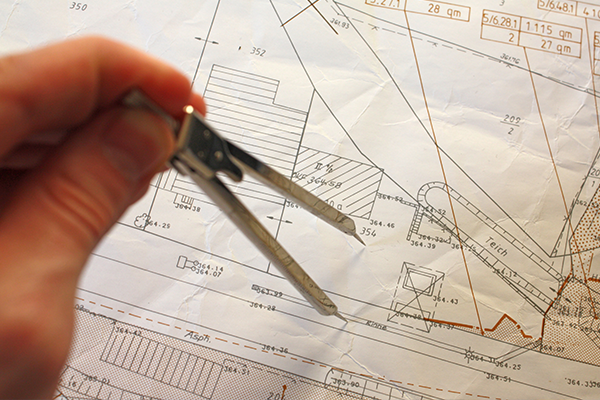 AN image of a surveyor looking over a house blueprint